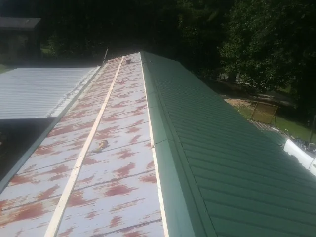 Old rusted panels beside newly installed green metal roofing — Wind Damage Roof Repair by Roofing Brothers in Wiota