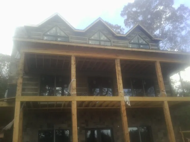 Dormers and porch framing on a large log home under construction — Roof Coating work by our crew in Wiota