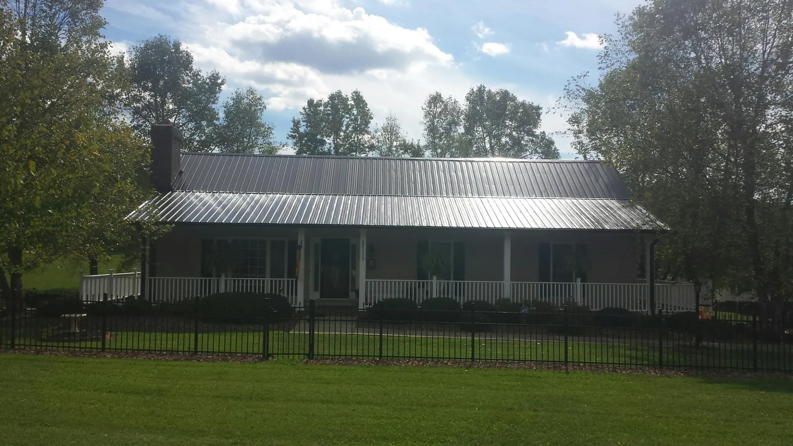 Gray metal roof on a brick ranch with a full width front porch — Gutter Guard Installation work by our crew in Wiota