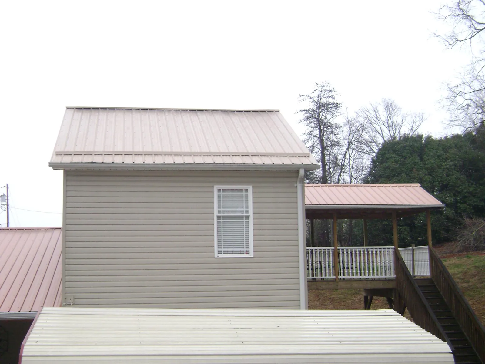 Tan metal roofs on a two story addition and attached porch, from a Roof Replacement job in Wiota