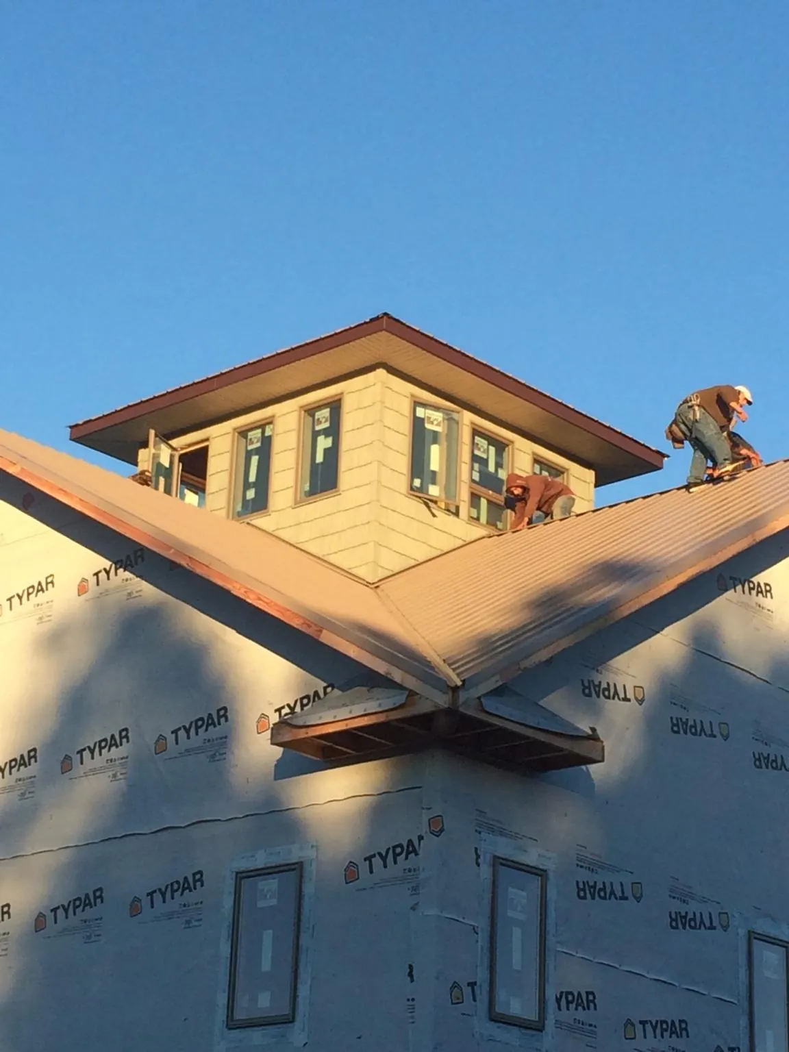 Roofers working around a rooftop cupola on a new metal roof at sunset — Roof Waterproofing in Wiota by Roofing Brothers